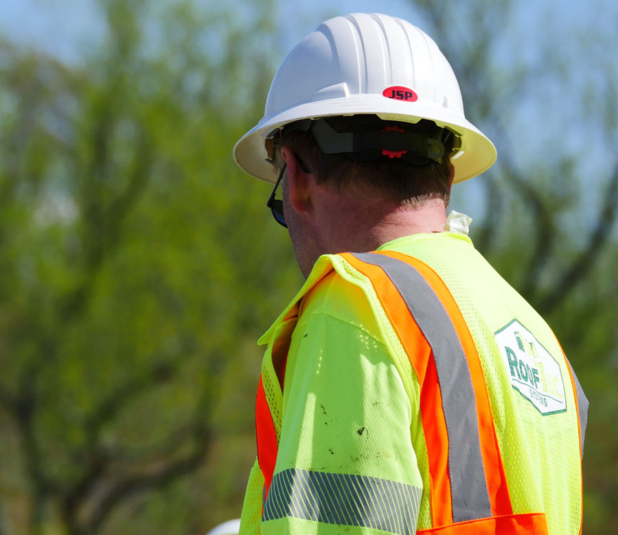A man in a construction vest and hardhat outdoors.